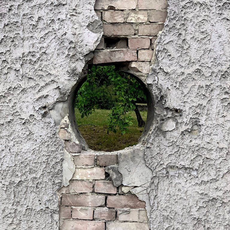 The hole in the wall is a foil for a lush green view encouraging the viewer to look through.